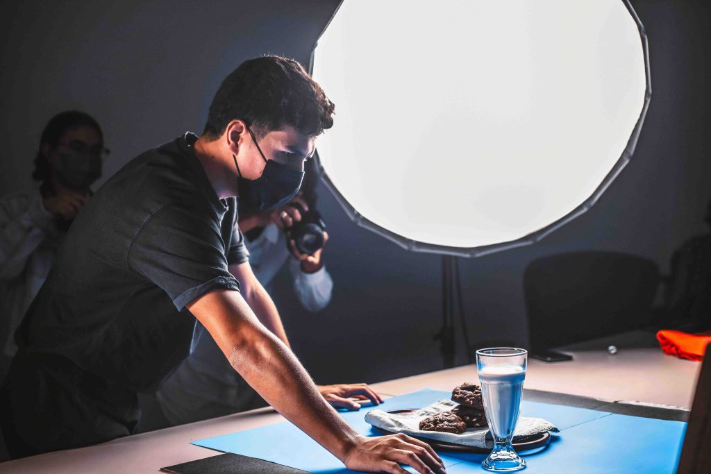 Photographer arranging food in a product photography studio with lighting